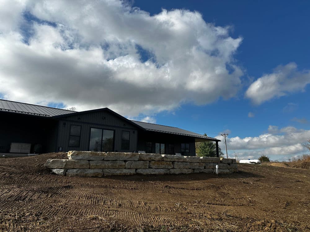 Modern home with stone landscaping, under a bright blue sky and fluffy clouds.